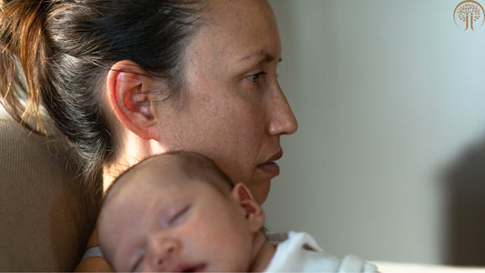 Mutter mit Wochenbettdepression sitzt erschöpft mit Baby